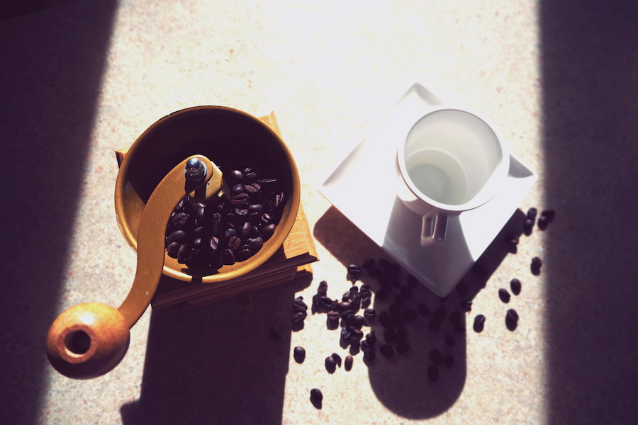 A coffee grinder near a white mug