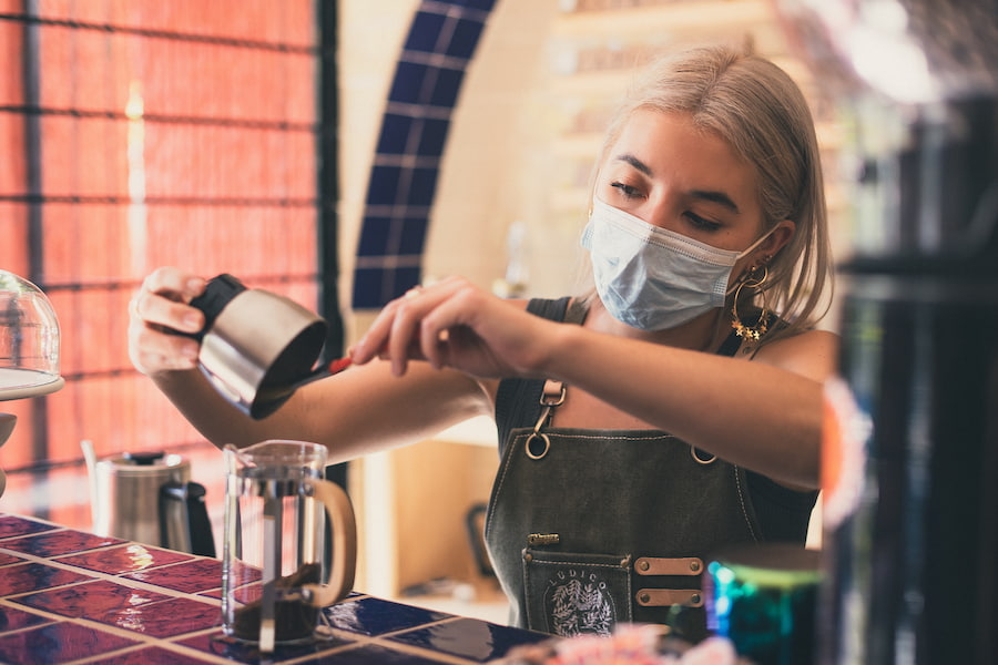 An image of a barista putting coffee grounds on a French press