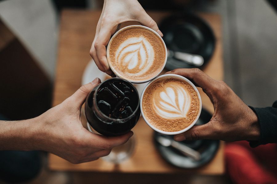 People holding cups of hot latte and an iced coffee