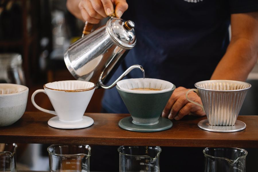 Barista using a gooseneck kettle to pour over coffee