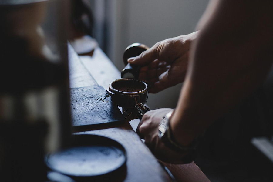 A person showing how to tamp an espresso