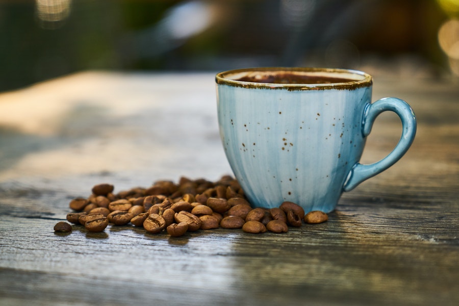 Coffee in a blue cup surrounded with coffee grounds