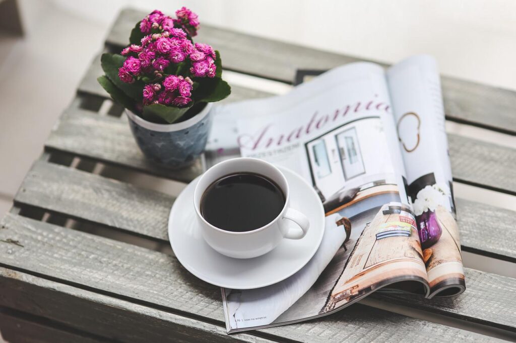 An image of a cup of coffee on top of an opened magazine