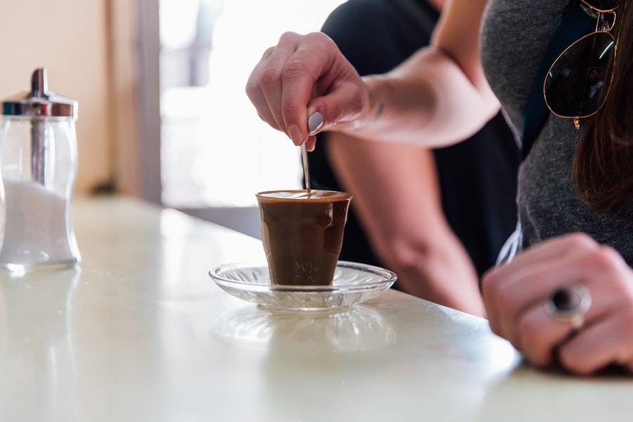 Person stirring coffee in a glass