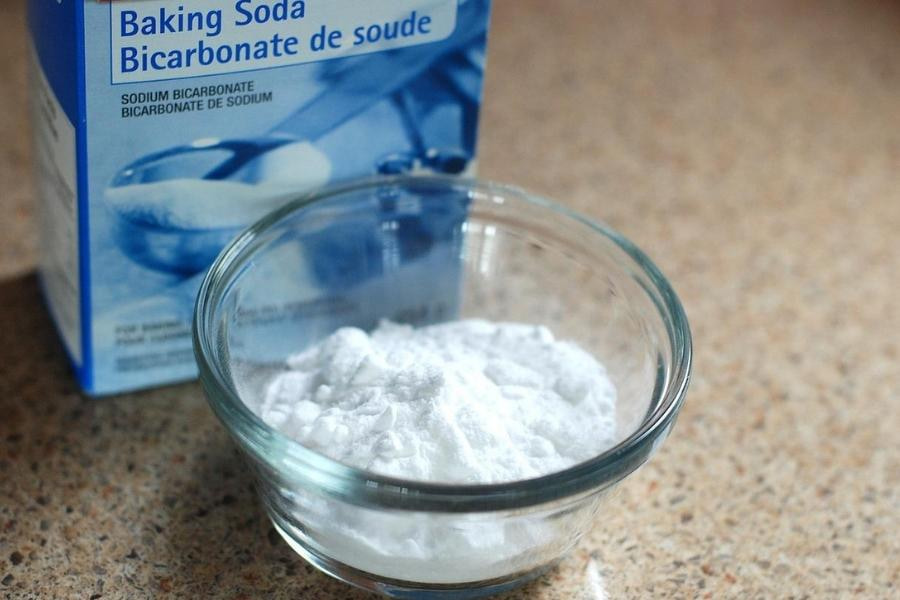 A box of baking soda in front of a clear bowl with baking soda placed on a granite top
