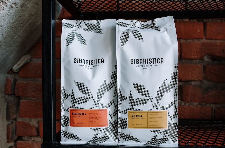 Two kinds of Sibaristica coffee were placed in a white pouch bag with a design of leaves on a black metal tray