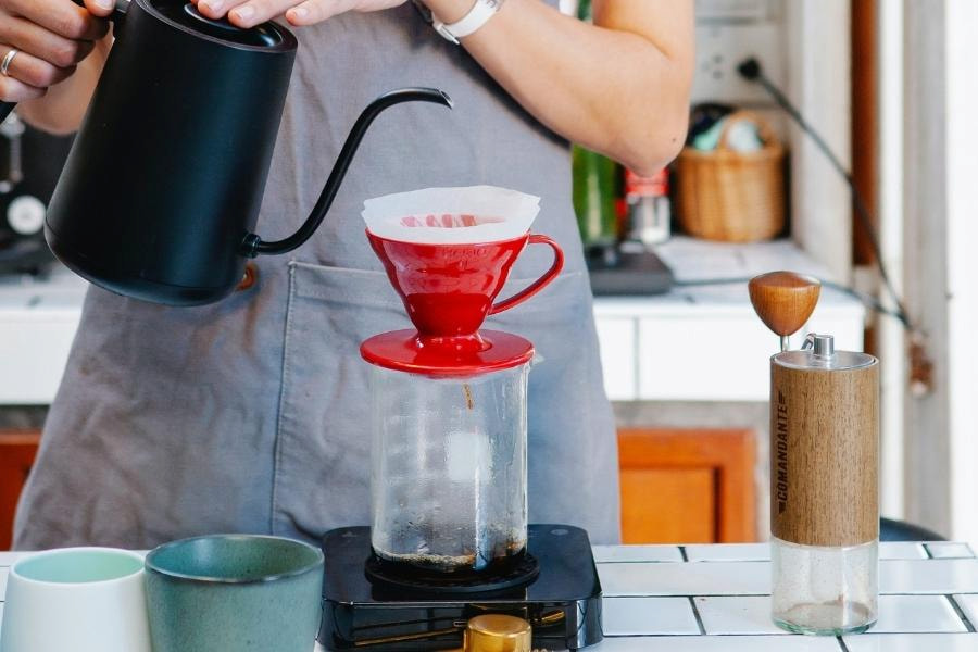 A person used a black pour-over coffee kettle to pour coffee into a pour-over coffee maker