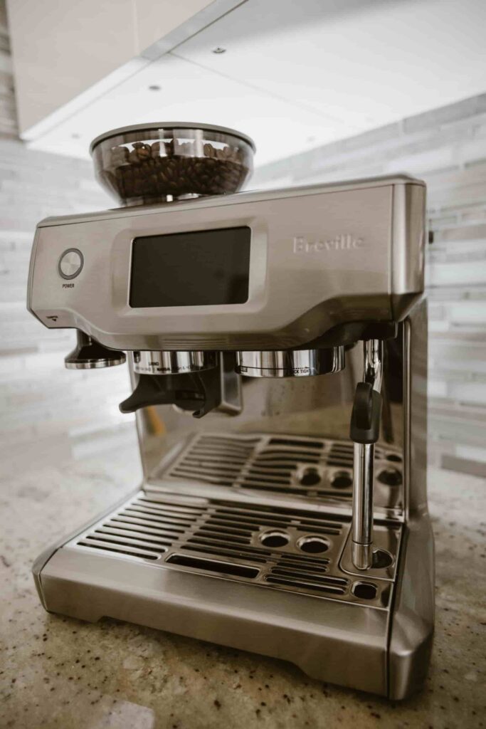 A silver Breville coffee machine on a granite countertop in a kitchen