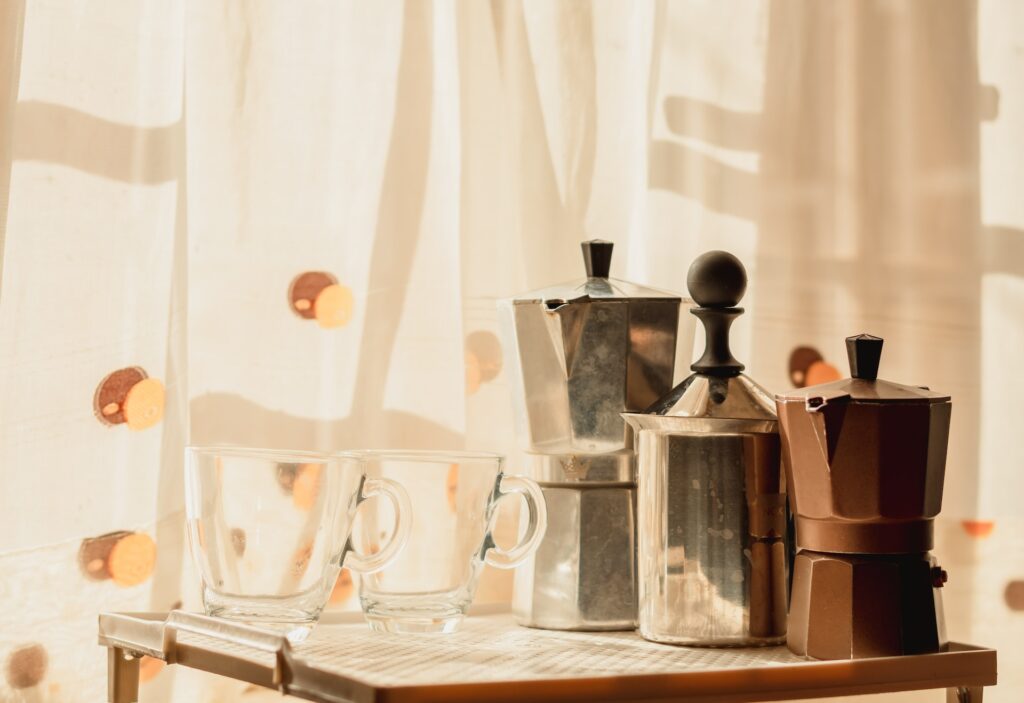 Three stainless Moka pots and two glasses were placed on top of a tray in the kitchen