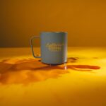 A coffee spilled from a coffee mug was placed on top of a yellow table inside a room