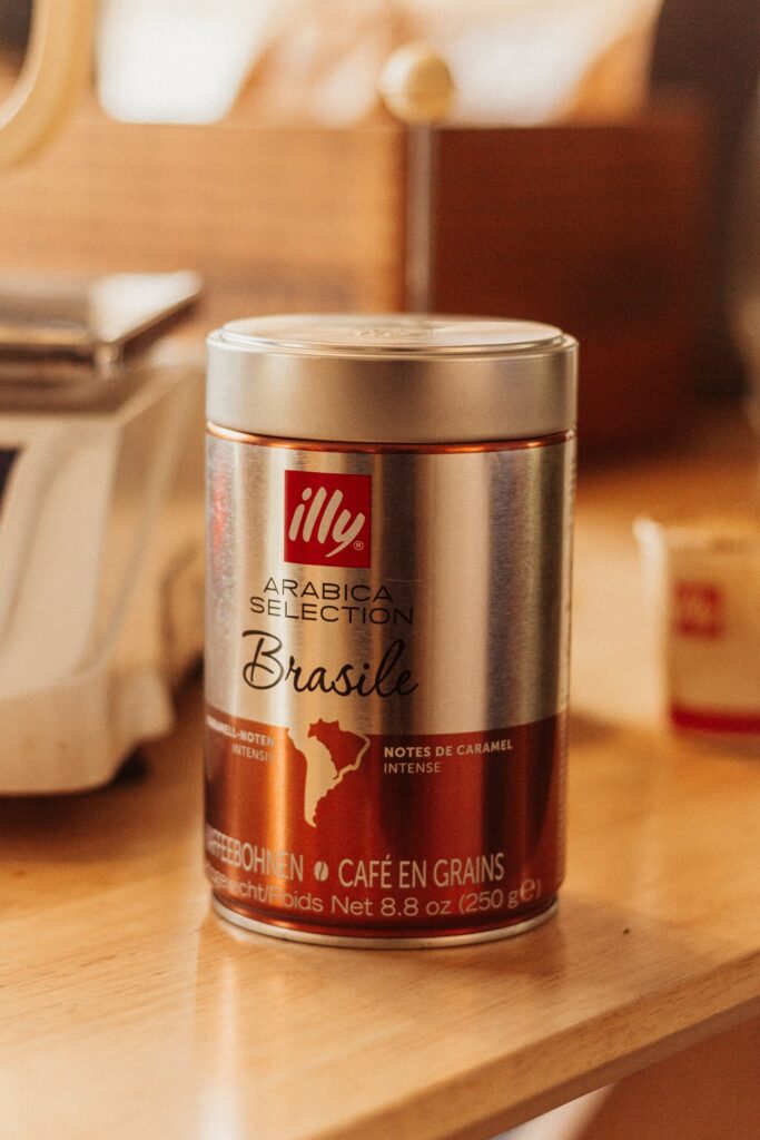 An aluminum can of Illy Arabica Selection with gold foil finish on top of a brown wooden table