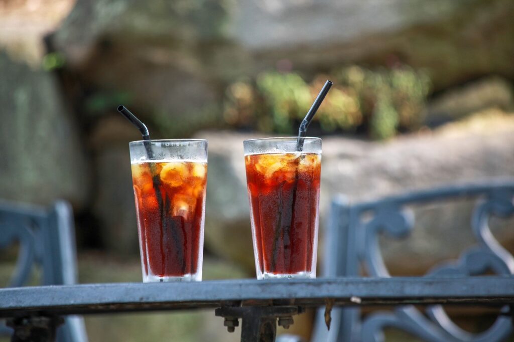 Two glasses of iced cold coffee with black straws placed on a table