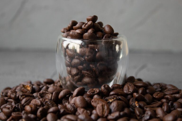 Arabica coffee beans on a shot glass and the table against a gray background