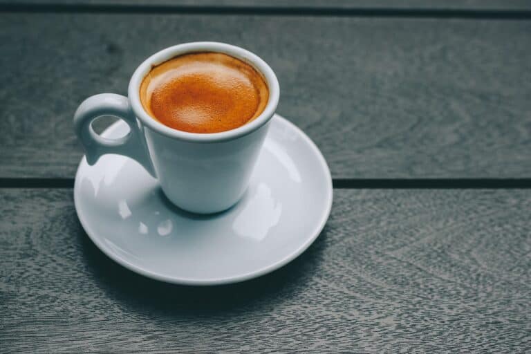 A white ceramic mug filled with espresso was placed on a white saucer