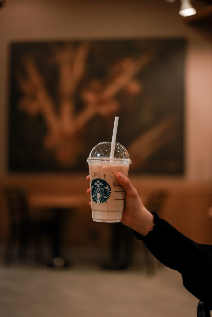 A person wearing black long sleeves holding an iced coffee from Starbucks