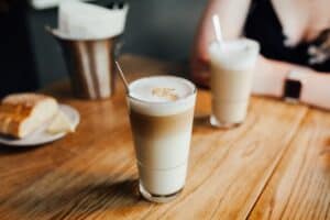 Two glasses of iced coffee with straws placed on a brown wooden table