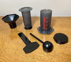 A complete set of AeroPress coffee maker placed on a brown wooden table