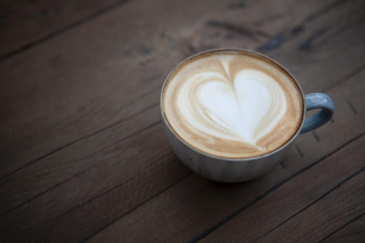 A blue mug filled with cappuccino coffee was placed on a brown wooden table