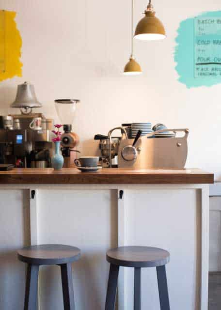 A coffee shop with an espresso machine, coffee filter, purple mugs, and chairs