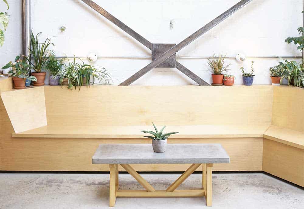 Coffee shop with long wooden chairs and a wooden table with a vase on top