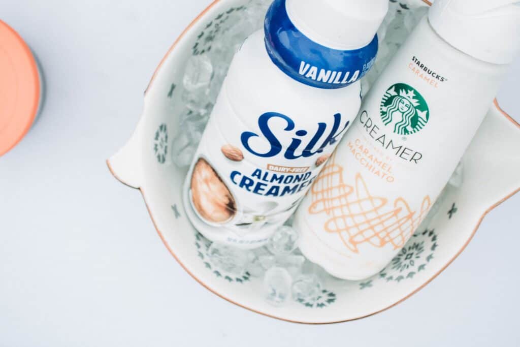 Silk Almond Creamer and Starbucks Caramel Creamer sitting in a green and white bowl on the kitchen counter