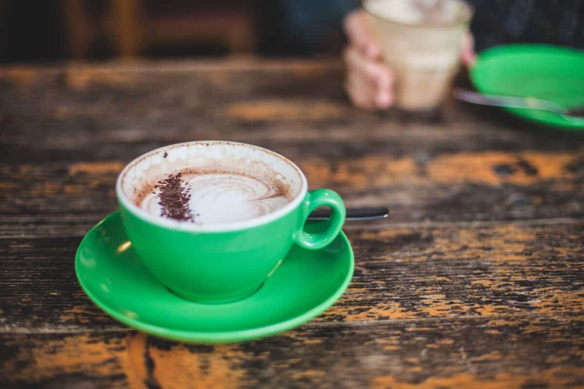 A green teacup with coffee on a green saucer was placed on a wooden table