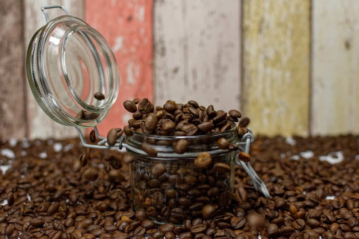 A mini mason jar overflowing with fresh coffee beans was placed near a wooden wall