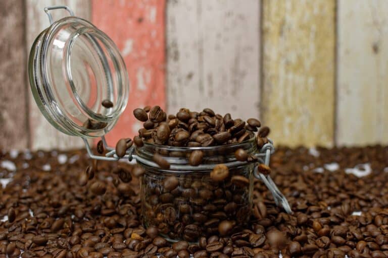 A mini mason jar overflowing with fresh coffee beans was placed near a wooden wall