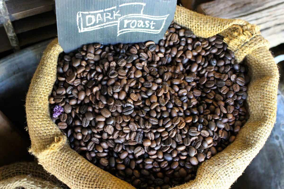 A yellow knitted sack filled with dark roast coffee beans was placed on a wooden surface