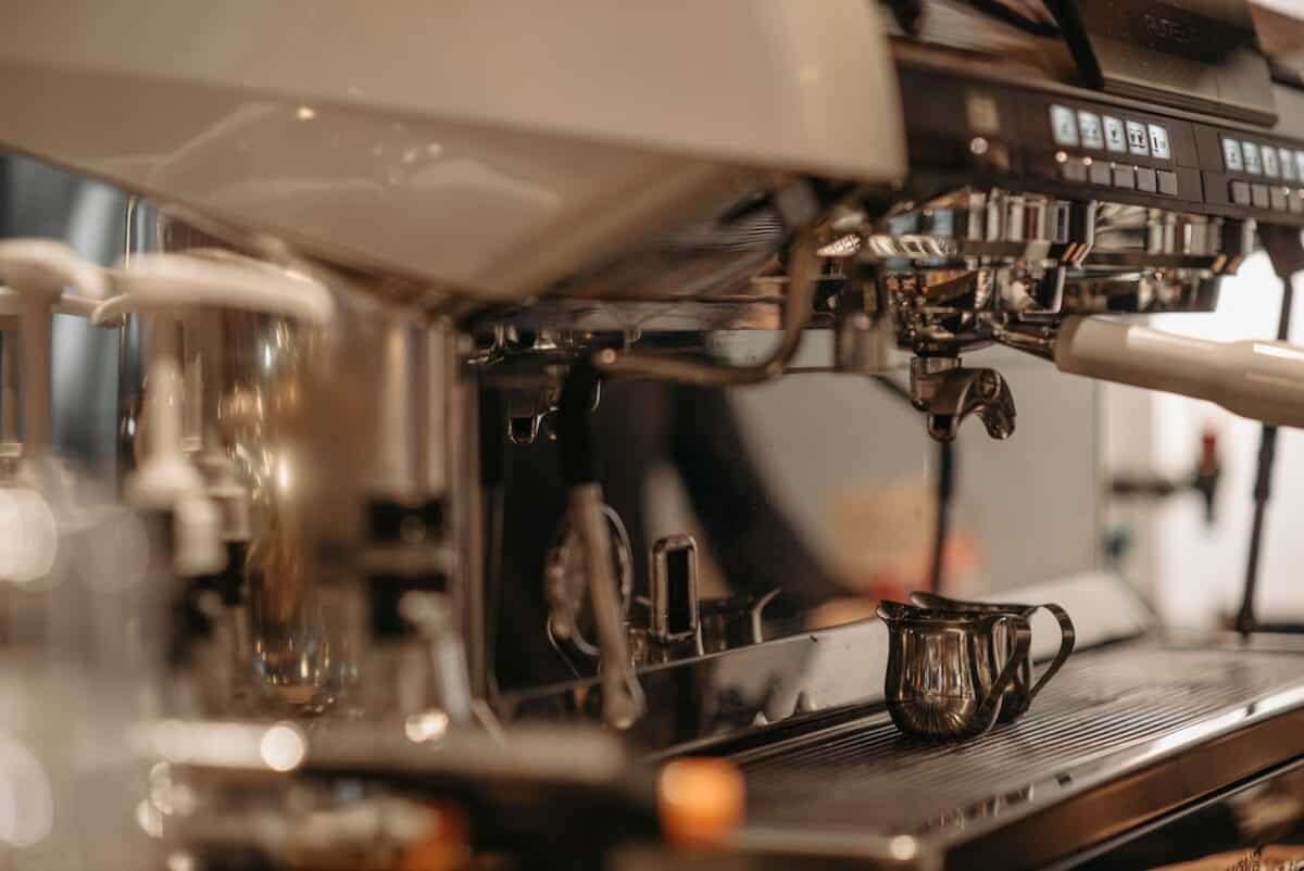 Close-up shot of an espresso machine with two stainless mugs and knock box