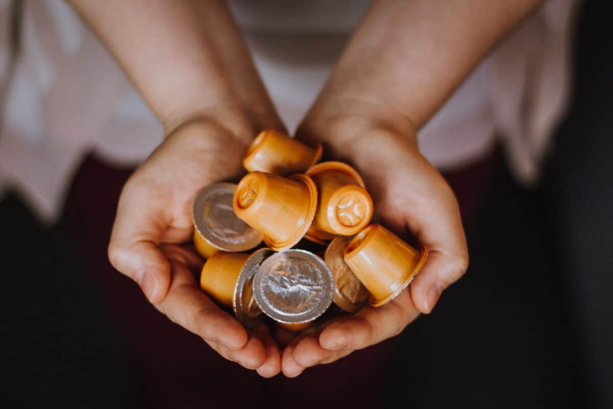 A person holding k-cups which are orange in color