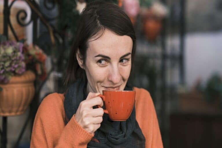 Woman holding an orange coffee cup near her lips